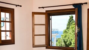A room with a blue sofa, a white coffee table, and a window with a view of trees and a building. - Hot Tub Cottage Kalymnos (Kalymnos)