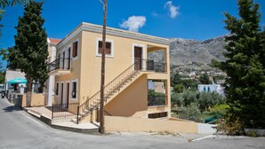 A two-story building with a staircase leading to the upper floor, a balcony, and a view of the surrounding landscape. - Hot Tub Cottage Kalymnos (Kalymnos)