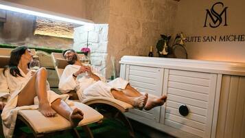Een spa-suite met twee relaxstoelen, een wit kastje en een stenen muur.