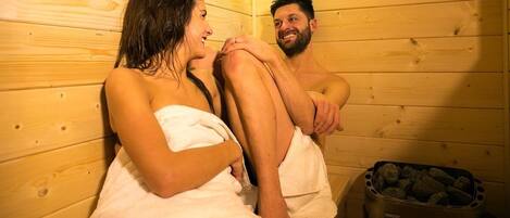 A sauna room with wooden walls and a stone container.