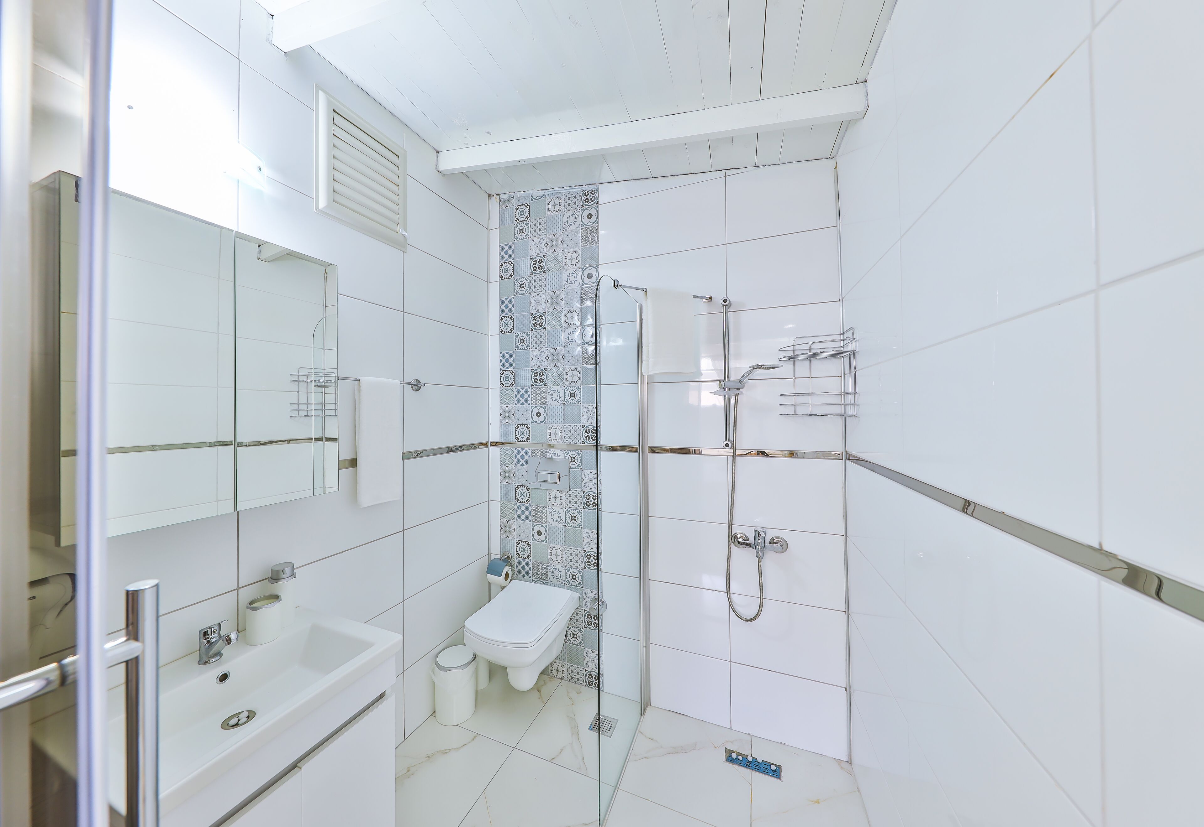 A modern bathroom with a glass-enclosed shower, a white sink, and a toilet.