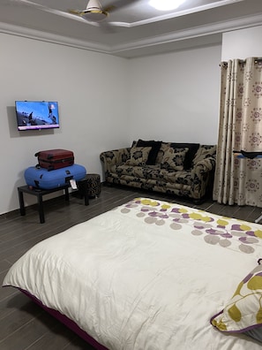 A bedroom with a bed, a suitcase, a TV, and a window. - 3-bed Apartment, Sleeps 6 With Wi-fi (Sakumono)