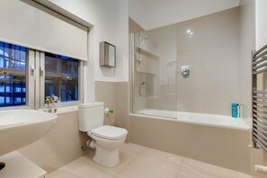 A modern bathroom with a toilet, sink, and glass-enclosed shower.