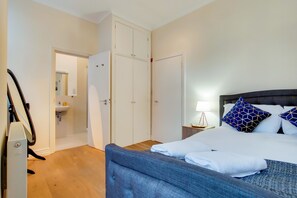 Hotellihuone, jossa on sänky, yöpöytä, lamppu, vaatekaappi ja kylpyhuone, jossa on pesuallas.