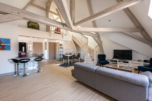 A spacious loft with a high ceiling, exposed wooden beams, a dining area, a living room with a sofa and TV, and a kitchen with modern appliances. - Le Palais, right in the heart of Dijon! (Dijon)