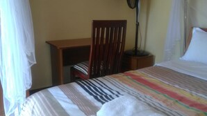 A room with a bed, a chair, a desk, and a nightstand. - Juliana County Hotel (Bondo)