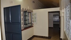 A hallway with a blue door, a white-framed window, and a tiled floor. - Juliana County Hotel (Bondo)