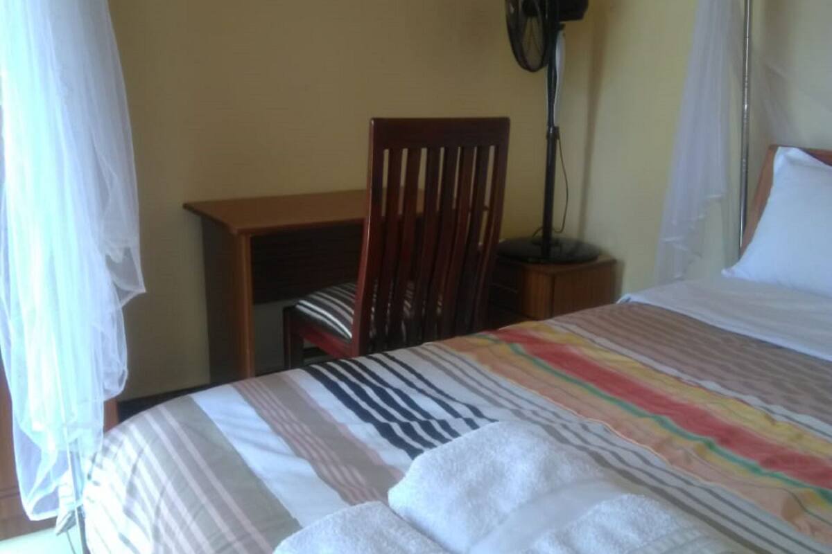 Una habitación con cama, una silla, un escritorio y una mesita de noche.