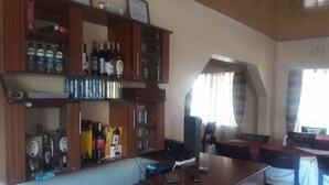 A dining area with a long wooden table, chairs, and a buffet counter with various food items and condiments. - Juliana County Hotel (Bondo)