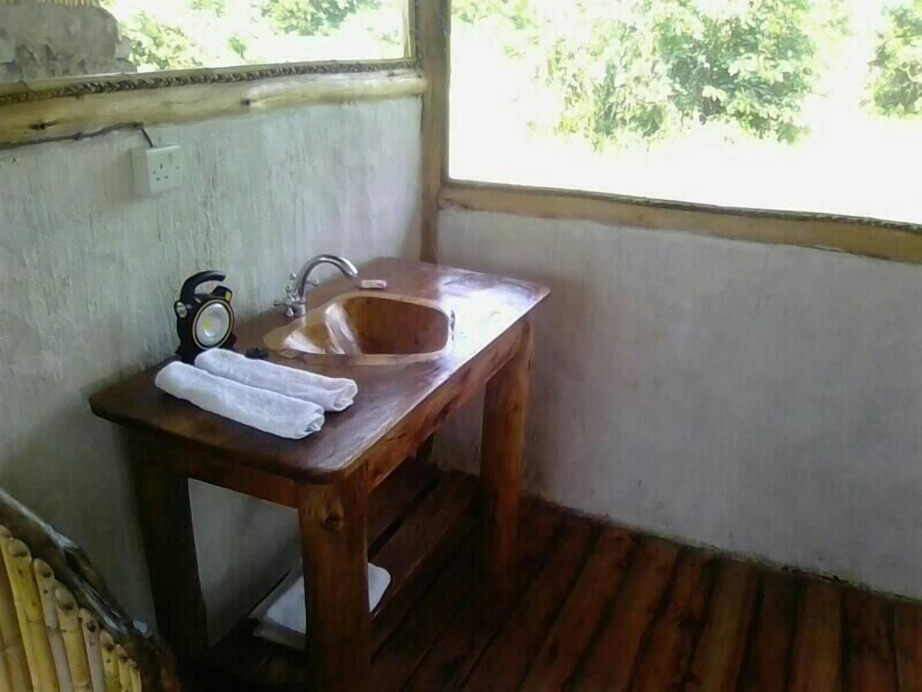 A small wooden sink with a faucet and a clock on the wall.