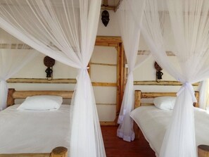A room with two wooden beds, each with white bedding and a canopy.