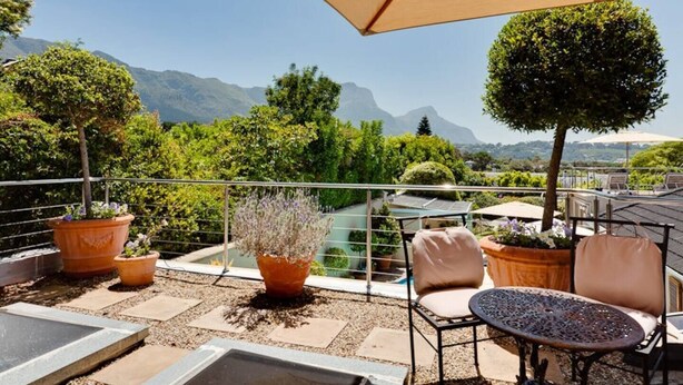 A terrace with potted plants, outdoor seating, and a view of mountains. - Lavender Cottage Upstairs 2 Bedrooms,2 Bathrooms with Magnificent mountain views (Cape Town)