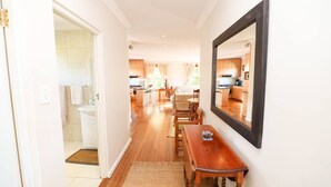 A hallway leading to a bathroom and a dining area with a wooden table and chairs. - Lavender Cottage Upstairs 2 Bedrooms,2 Bathrooms with Magnificent mountain views (Cape Town)