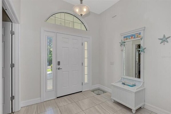 A hallway with a white door, a small vanity with a mirror, and a ceiling light fixture.
