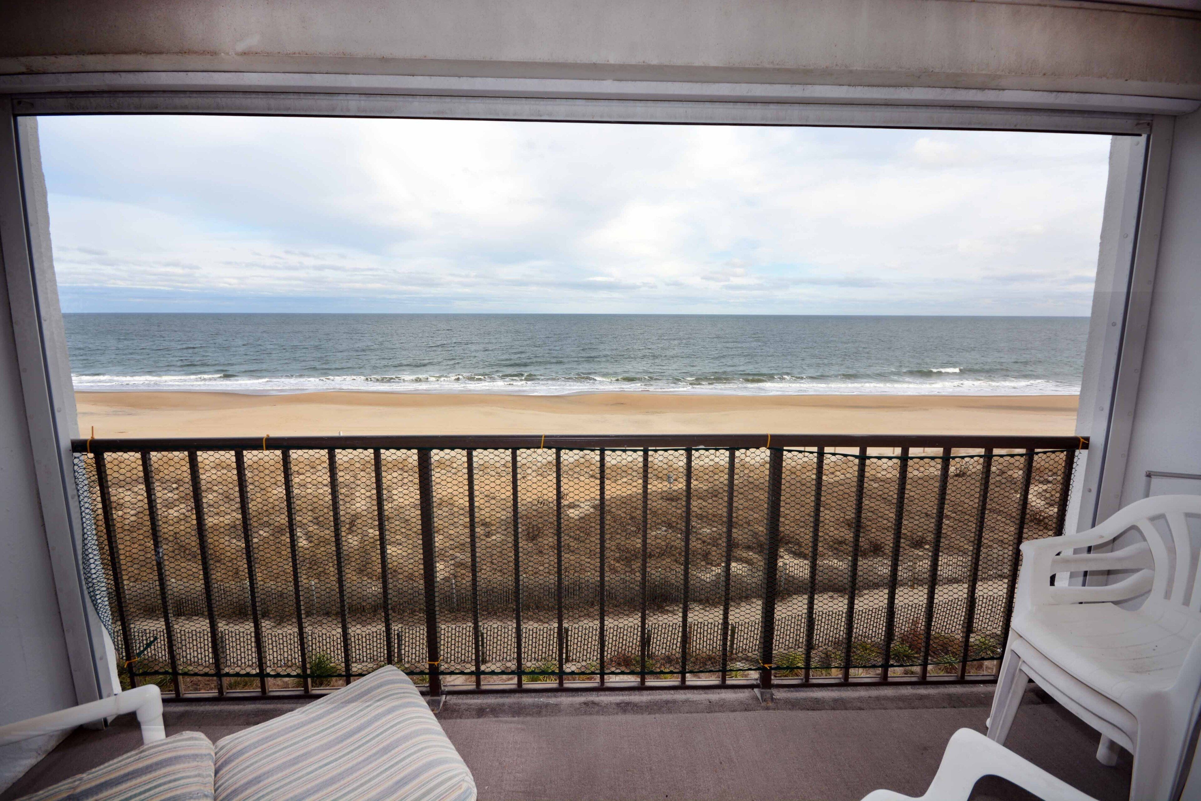 A balcony with a view of the beach and ocean.