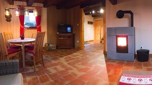 Ein gemütliches Wohnzimmer mit Kamin, Fernseher und einer Essecke mit Stühlen und Tisch.