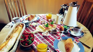 Ein Frühstückstisch mit Croissants, Erdbeeren, einem Glas Orangensaft und einer Kaffeekanne.