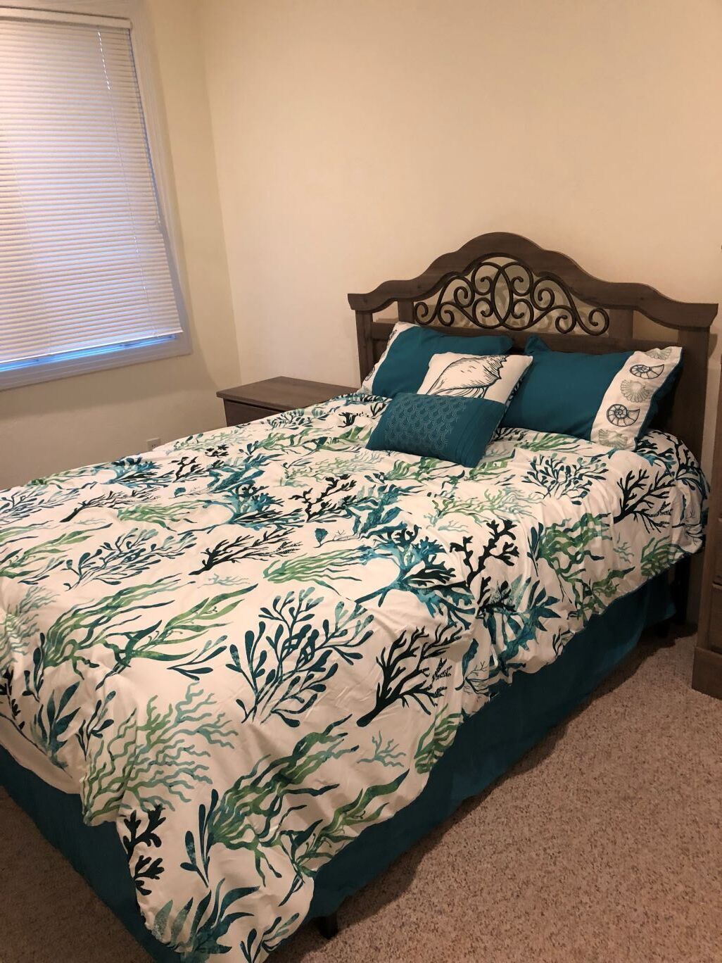 Un lit avec une couvre-lit à motifs floraux, une tête de lit en bois et deux tables de chevet.