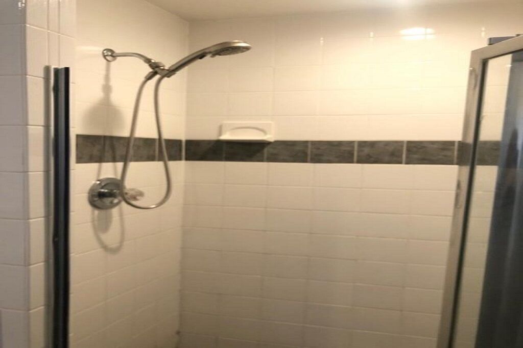 A shower with a handheld showerhead and a wall-mounted faucet.