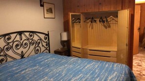 A bedroom with a bed, a wardrobe, and a nightstand.