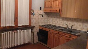 A compact kitchen with wooden cabinets, a built-in stove, and a sink.