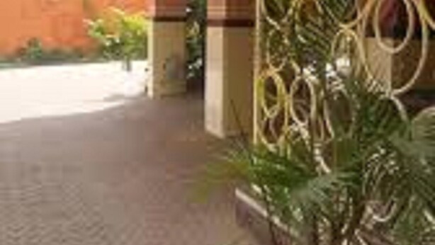 A building entrance with a tiled walkway, a potted plant, and a decorative metal fence. - Lighthomez Pinnacle Suites (Nairobi)