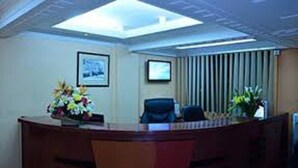 A conference room with a glass ceiling, a desk with a vase of flowers, and two framed pictures on the wall. - Lighthomez Pinnacle Suites (Nairobi)