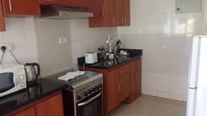 Uma cozinha compacta com armários de madeira, micro-ondas, fogão e geladeira.