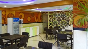 A modern dining area with a central table and chairs, a refrigerator, and a decorative wall with circular patterns. - Lighthomez Pinnacle Suites (Nairobi)