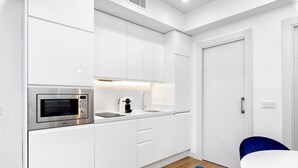 Una cocina moderna con armarios blancos, microondas integrado y un lavamanos.