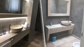 Et moderne badeværelse med et stort spejl, en rund vask og et toilet.