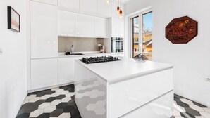 A modern kitchen with white cabinetry, a central island, and a hexagonal patterned floor.