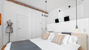 A modern bedroom with a large bed, a bedside table, a lamp, and a wardrobe.
