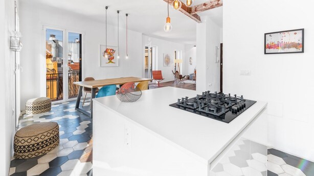 A modern kitchen with a central island, a dining area with a wooden table, and a patterned floor.