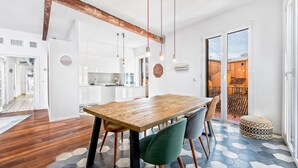 A modern kitchen with white cabinets, a wooden dining table, and a hexagonal patterned floor.