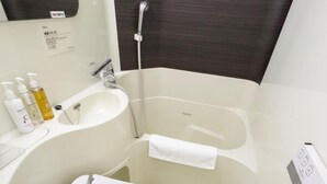 A modern bathroom with a white toilet, a sink, and a bathtub. - Super Hotel Ikebukuro Nishiguchi (Tokyo)