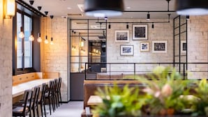 A modern restaurant interior with exposed brick walls, pendant lighting, and framed pictures on the wall. - Super Hotel Ikebukuro Nishiguchi (Tokyo)