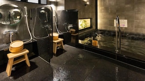A modern bathroom with a hot tub, wooden stools, and a mirror. - Super Hotel Ikebukuro Nishiguchi (Tokyo)