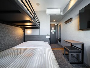 Quarto de hotel com cama beliche, mesa de cabeceira, televisão de tela plana e aparelho de ar condicionado.