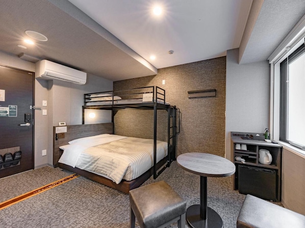 Quarto com beliche, uma mesinha, um banco, janela e ar condicionado.