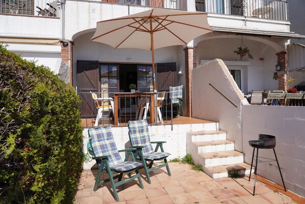 A patio with two green chairs, a large umbrella, and a table. - Torre vella 137 - L'Estartit, Torre Vella (Estartit (L´))