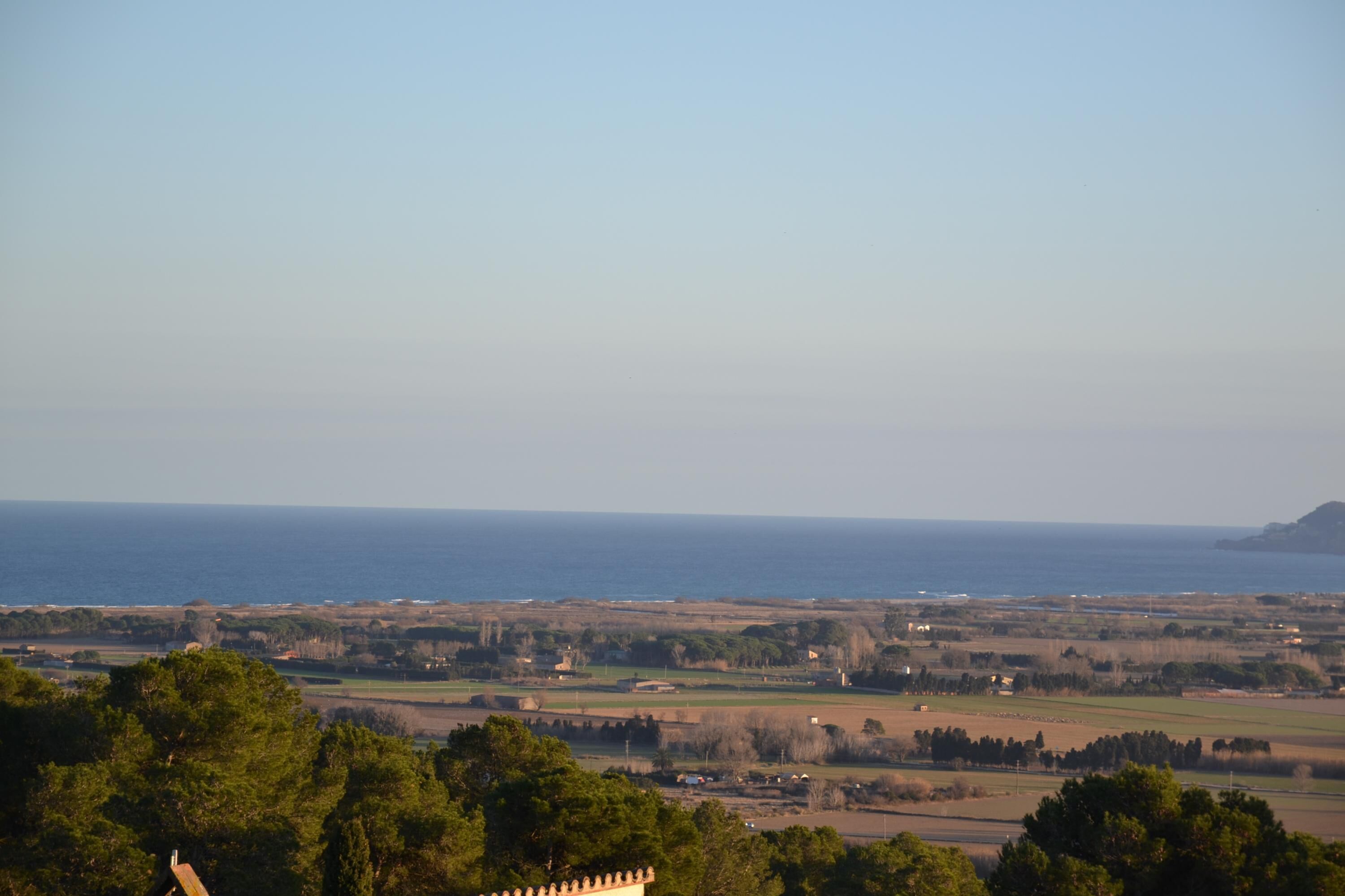 A coastal landscape with a view of the sea and distant hills.