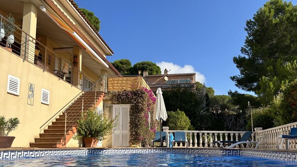 A swimming pool with a tiled edge, a staircase leading to a balcony, and a building with a balcony and potted plants. - Villa Urgell - L'Estartit, Torre Vella (Estartit (L´))