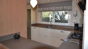 A modern kitchen with a large window, a built-in stove, and a hanging light fixture. - Villa Urgell - L'Estartit, Torre Vella (Estartit (L´))