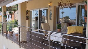 A balcony with potted plants, a table with a yellow tablecloth, and a chair. - Villa Urgell - L'Estartit, Torre Vella (Estartit (L´))