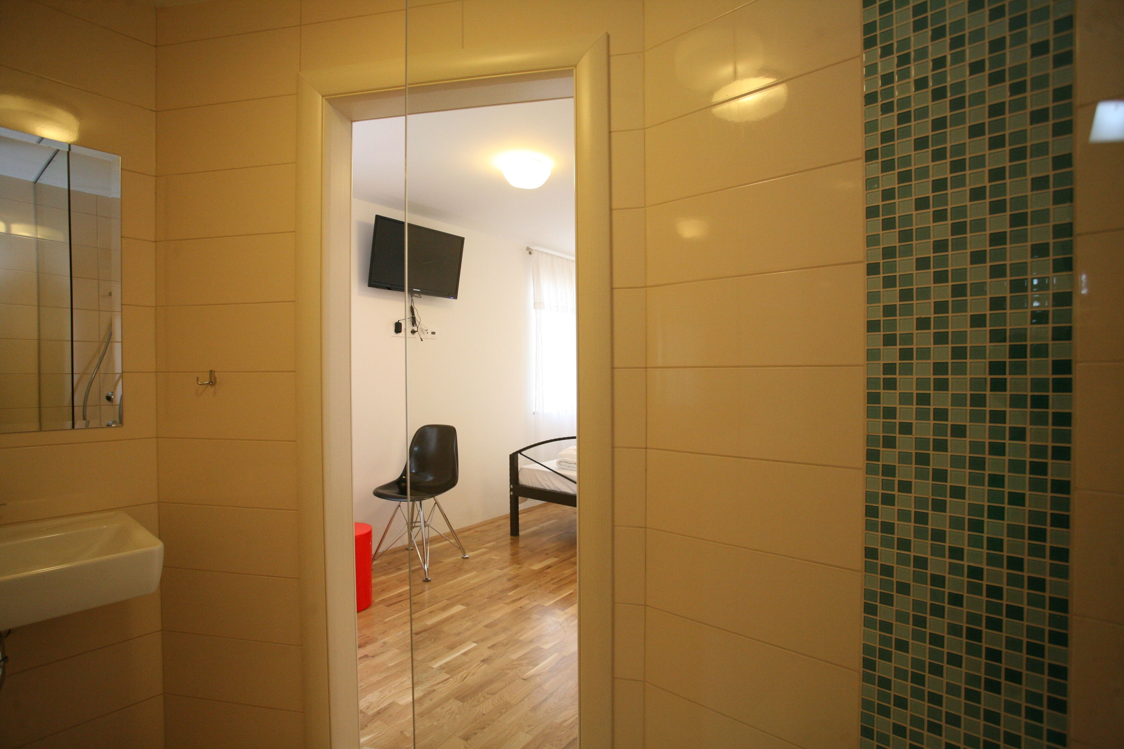 Une chambre d’hôtel comprenant une salle de bain, un lit, un téléviseur fixé au mur et une chaise.
