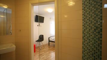 Une chambre d’hôtel comprenant une salle de bain, un lit, un téléviseur fixé au mur et une chaise.