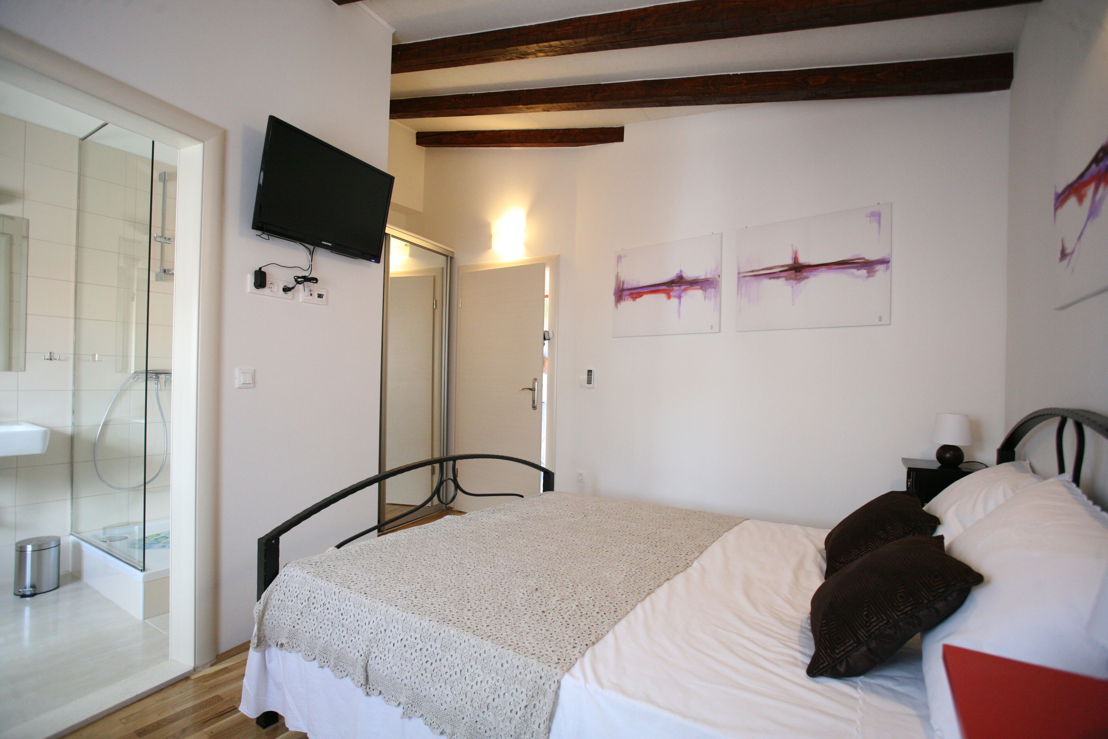 Un dormitorio con cama, televisión y obras de arte en la pared.