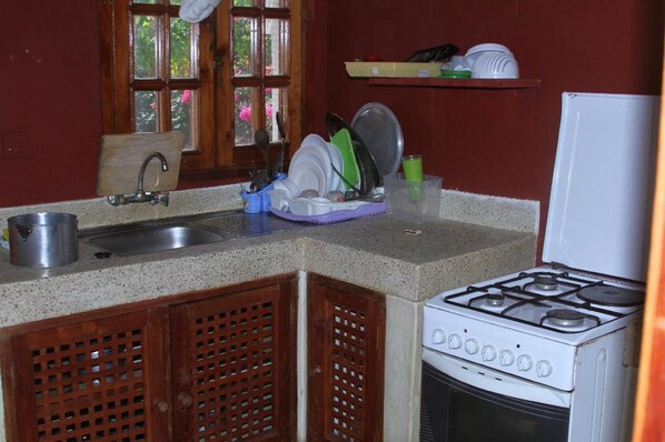A kitchen with a sink, stove, and dish drying rack.