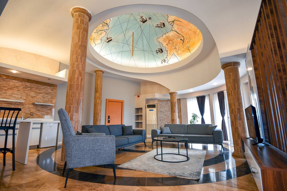 A spacious lobby with a large globe ceiling, modern furniture, and a kitchen area.